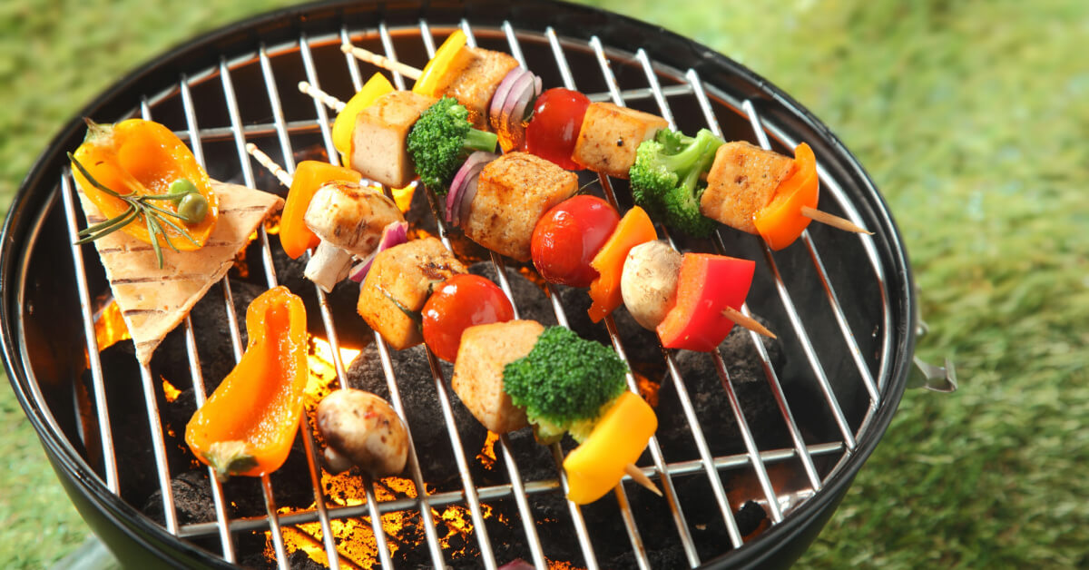 Tofu kebabs with colorful fresh vegetables including onion, sweet pepper, tofu,mushroom, broccoli and tomato threaded on skewers grilling over the fire on a BBQ